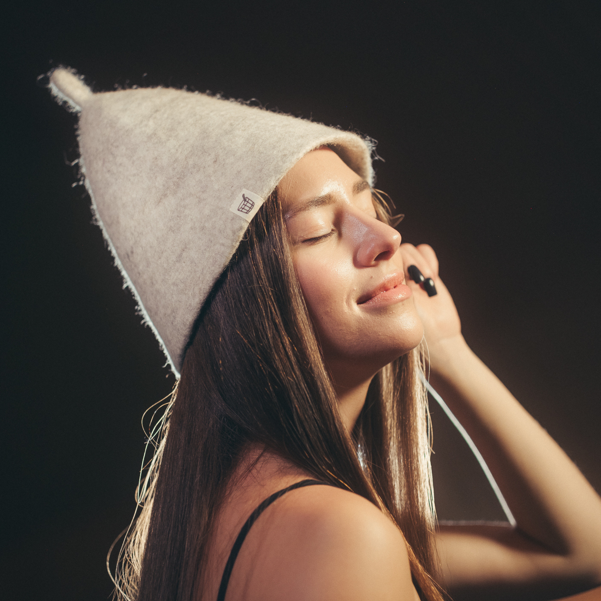 Woman wearing white wool sauna hat in sauna setting