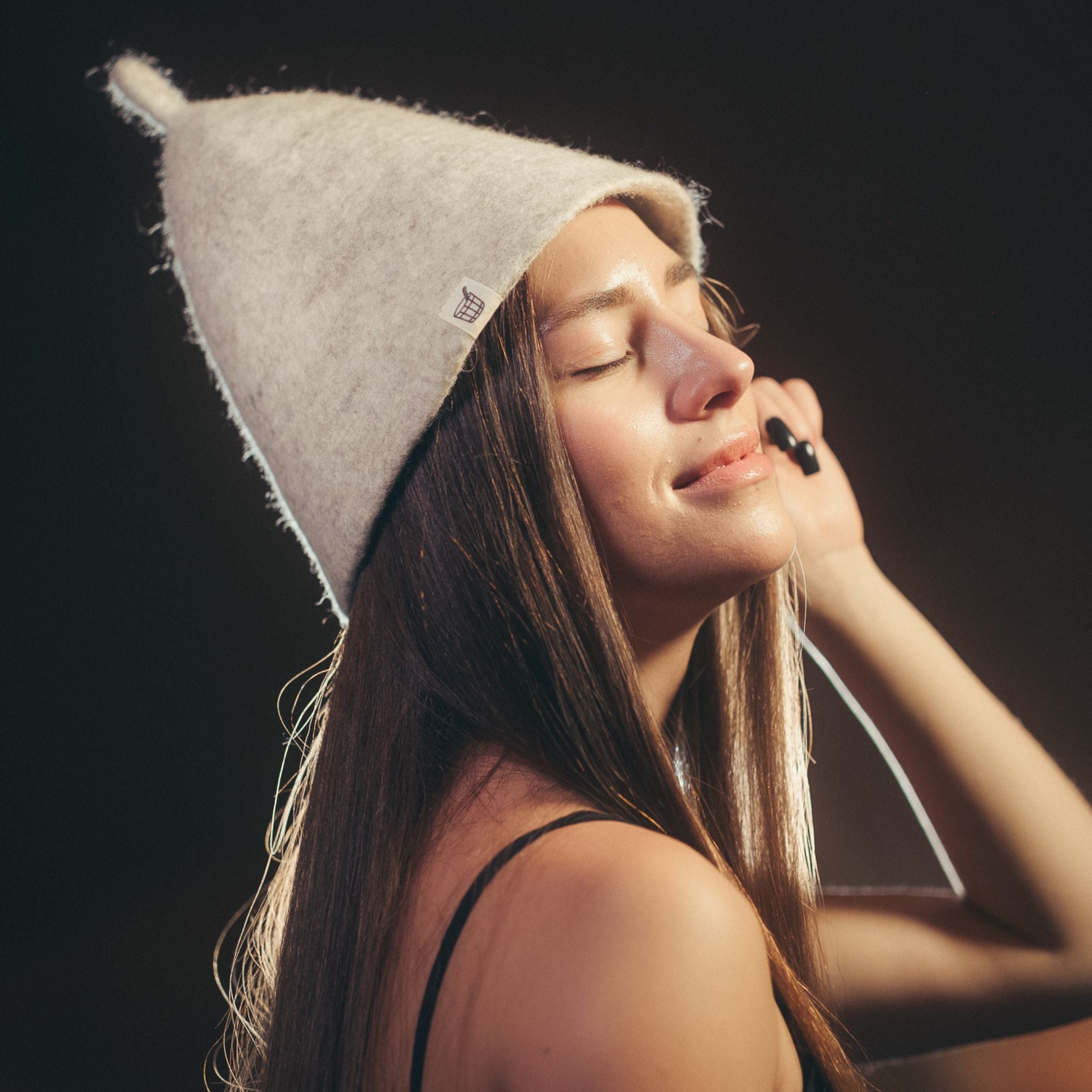 Woman wearing Nordic Birch wool sauna hat in sauna setting