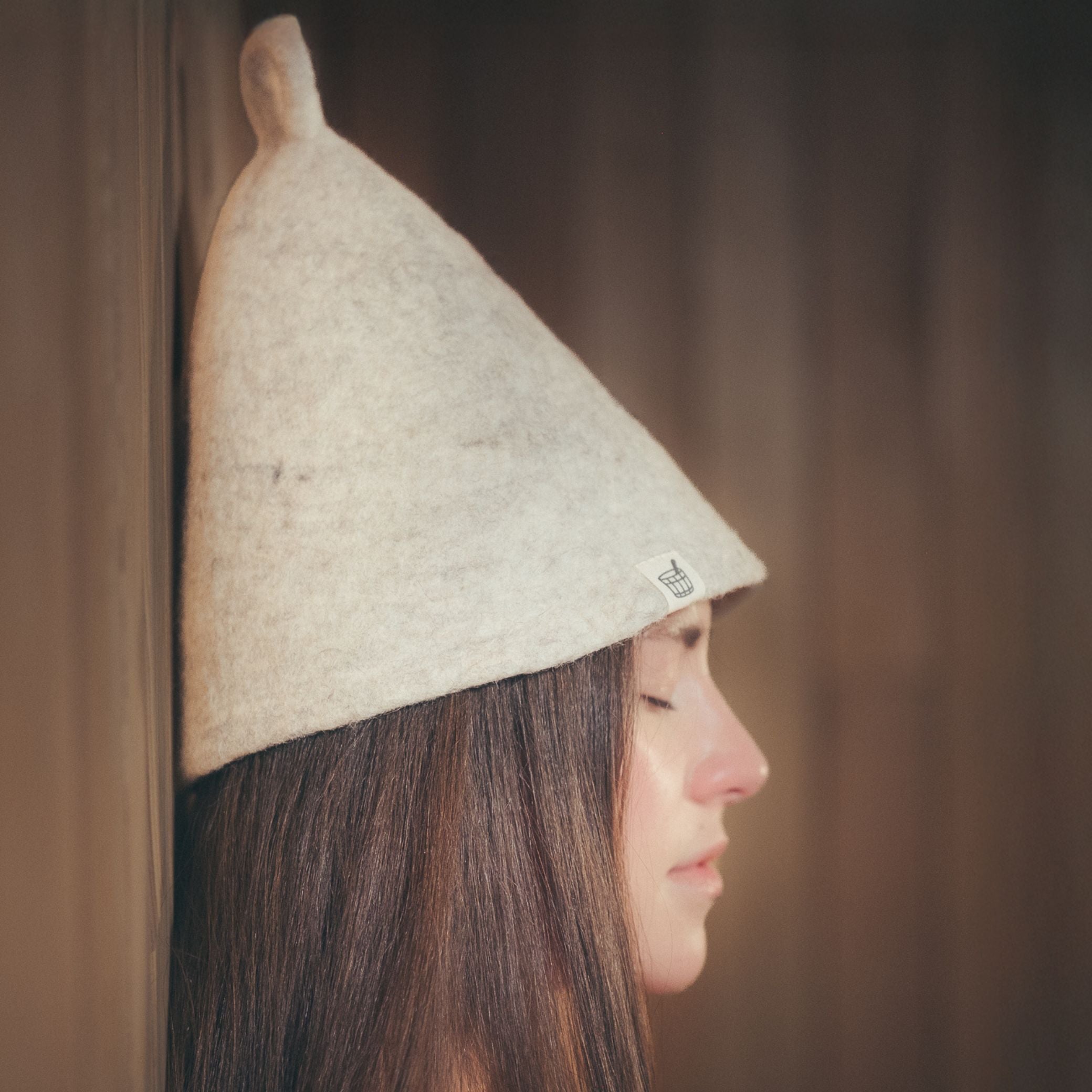 Woman wearing Nordic Birch wool sauna hat in sauna setting